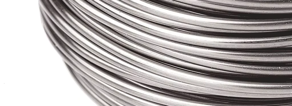 Close-up of shiny steel wire coils wound in parallel, forming concentric circles on a spool surface.