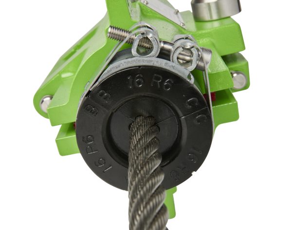 Close-up of a green metal clamp with a braided rope threaded through metal fittings and a black dial gear piece